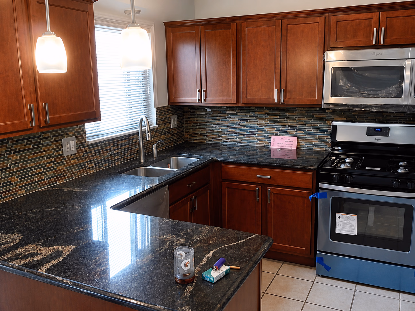 Kitchen with dark granite countertops, wooden cabinets, stainless steel appliances, and tiled floor.
