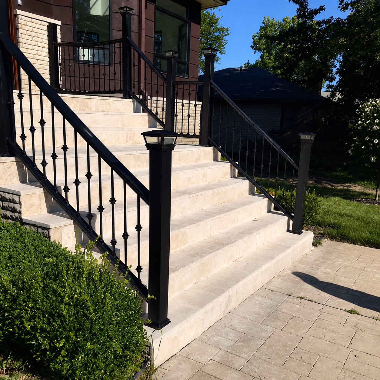 Outdoor beige stone stairs with black metal railings and lamp posts leading to a building entrance.
